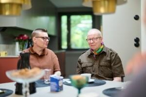 Kaksi sateenkaarisenioria istuu rinnakkain kahvipöydän ääressä.