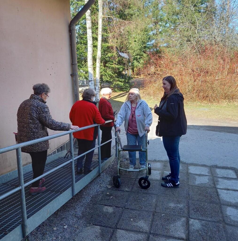 Neljä iäkästä ihmistä siirtyy ulos ramppia pitkin. Yksi rollaattorin avustuksella.