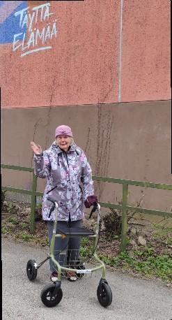 Iäkäs nainen rollaattorin kanssa ulkona. 