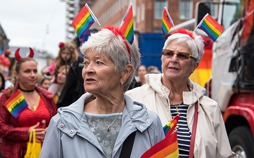 Ihmisiä pride-kulkueessa. Etualalla kaksi iäkästä naista.