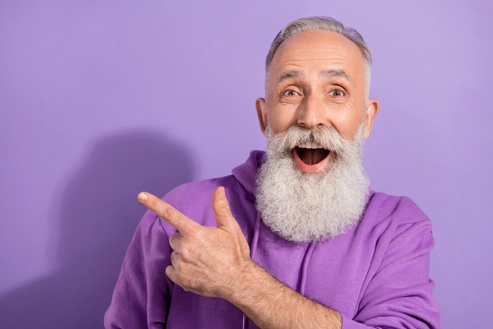 Portrait of attractive elderly retired pensioner trendy grey-haired man showing cool offer isolated over purple violet color background
