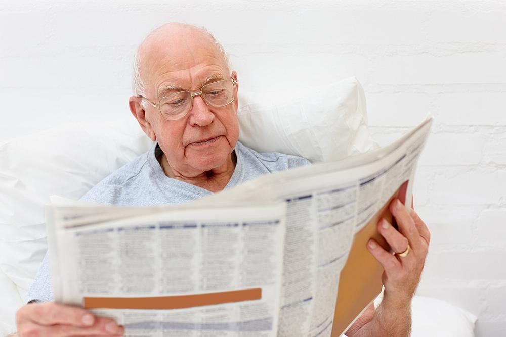 Medialukutaito. Vanha mies lukee sanomalehteä.