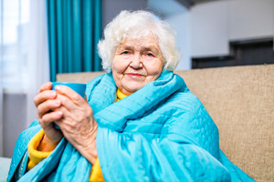 Vanha nainen katsoo kameraan kahvikuppi kädessä. VTKL aluevaalit teemakuva.