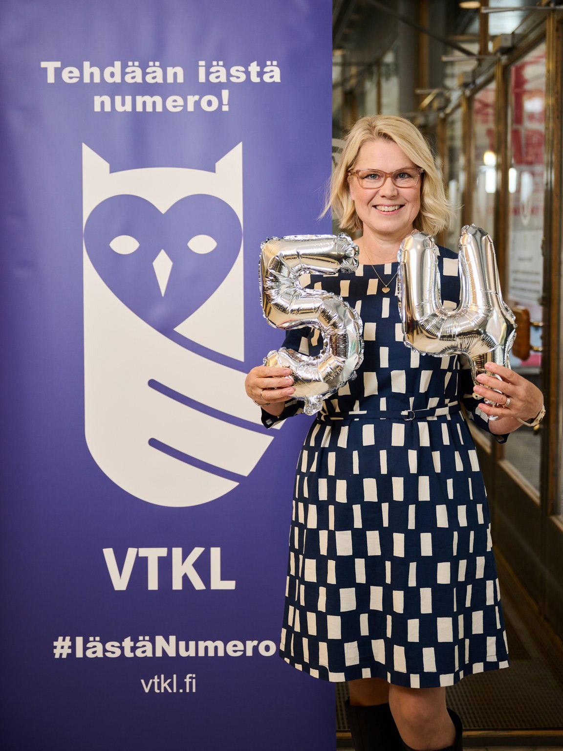 Tehdään iästä numero banneri. Kuvassa Eva Korkiämäki näyttää ikänsä ilmapalloilla. 54 vuotta.