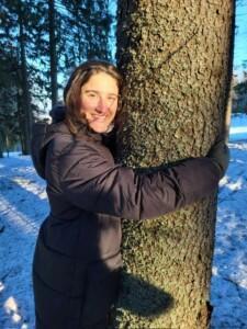 Nainen halaa puuta talvisessa metsässä.