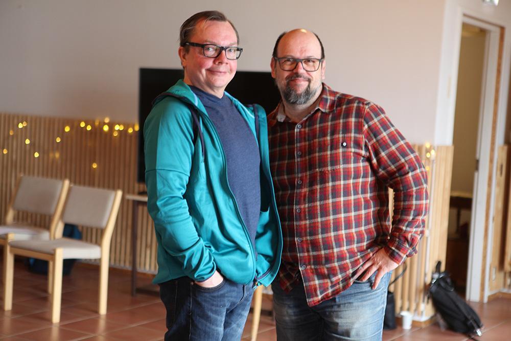 Kaksi keski-ikäistä miestä seisoo ja katsoo kameraan.