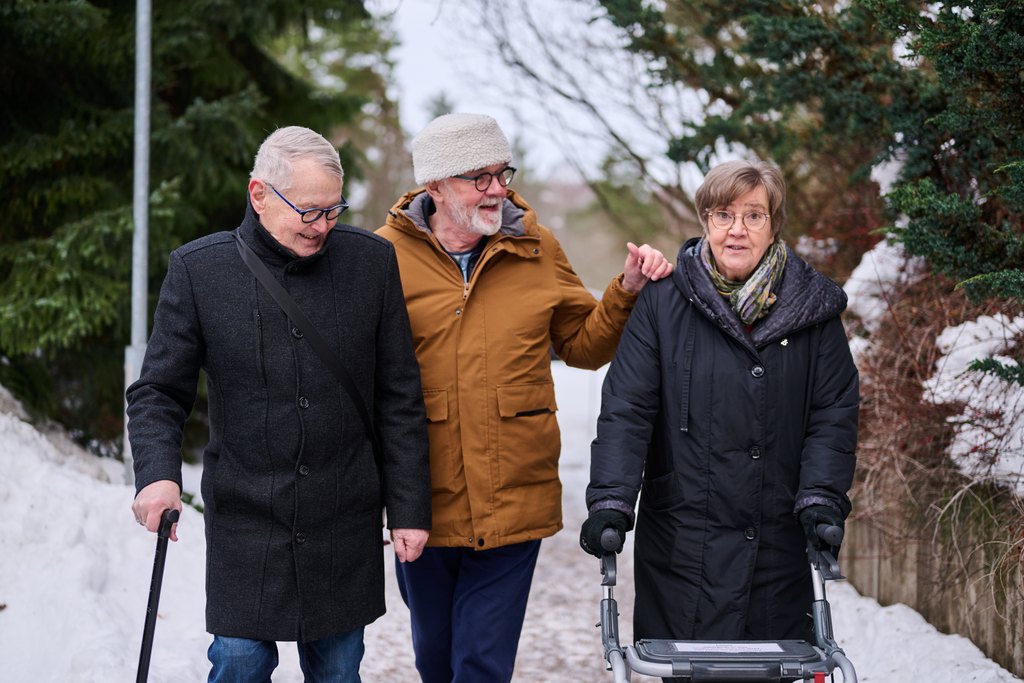 Kolme iäkästä henkilöä ulkona kävelemässä.