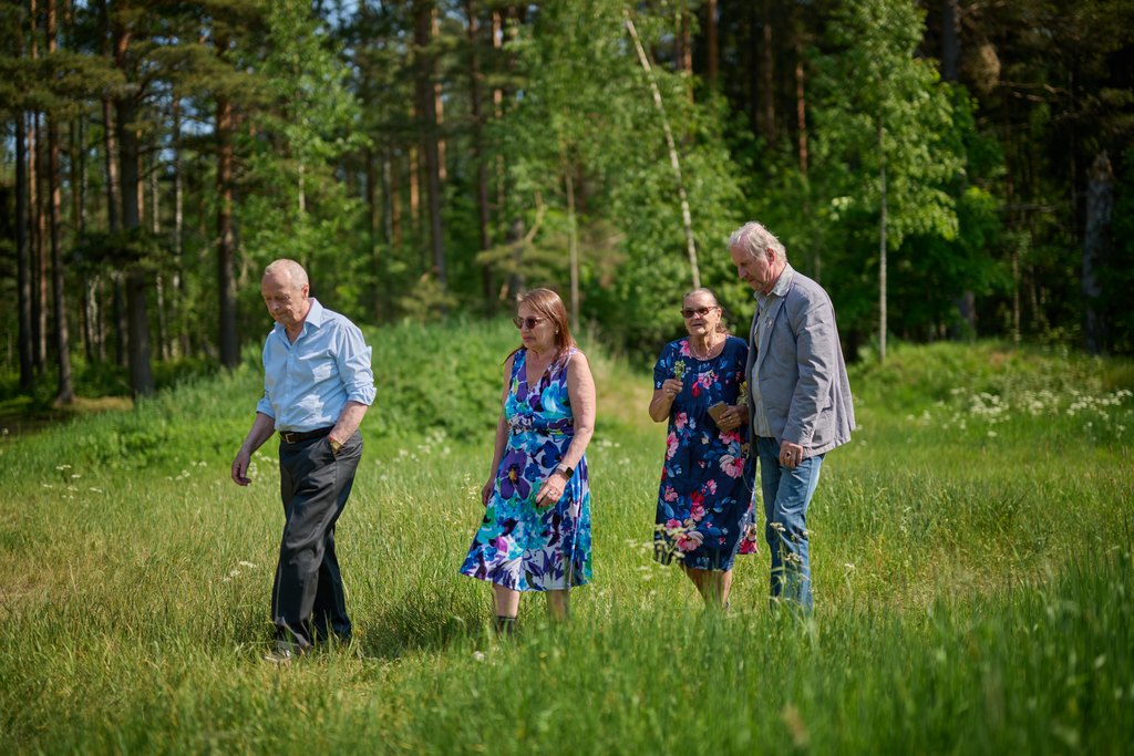 Fyra äldre personer promenerar tillsammans på en åker.