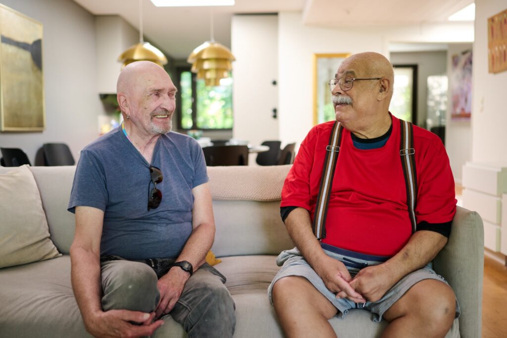 Kaksi iäkästä miestä istumassa olohuoneen sohvalla.