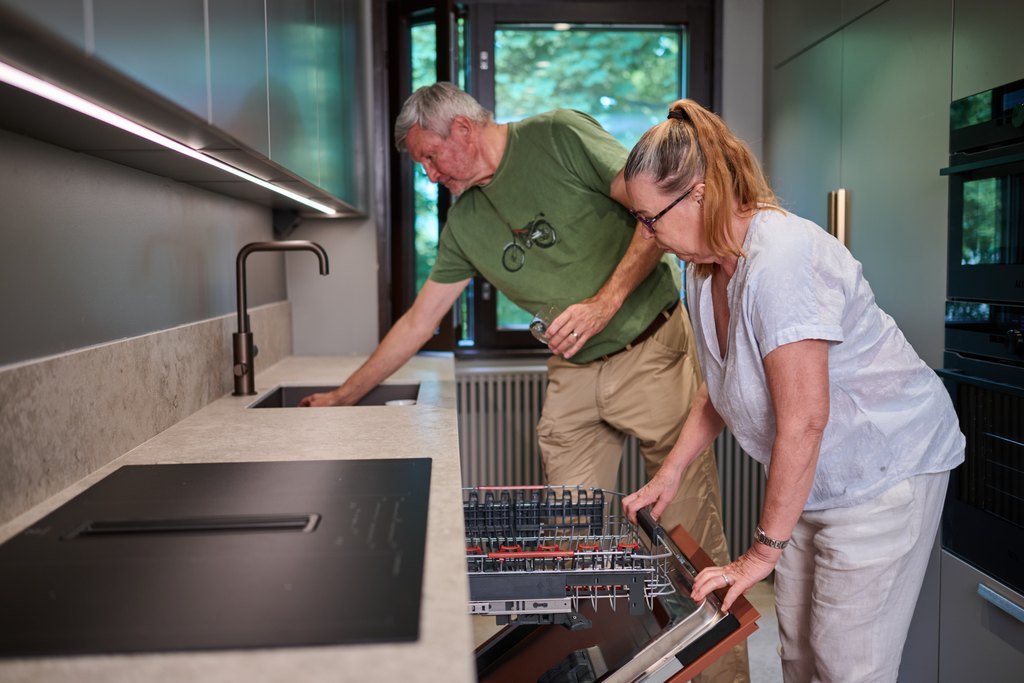 Iäkäs pari tiskaa astioita keittiössä.