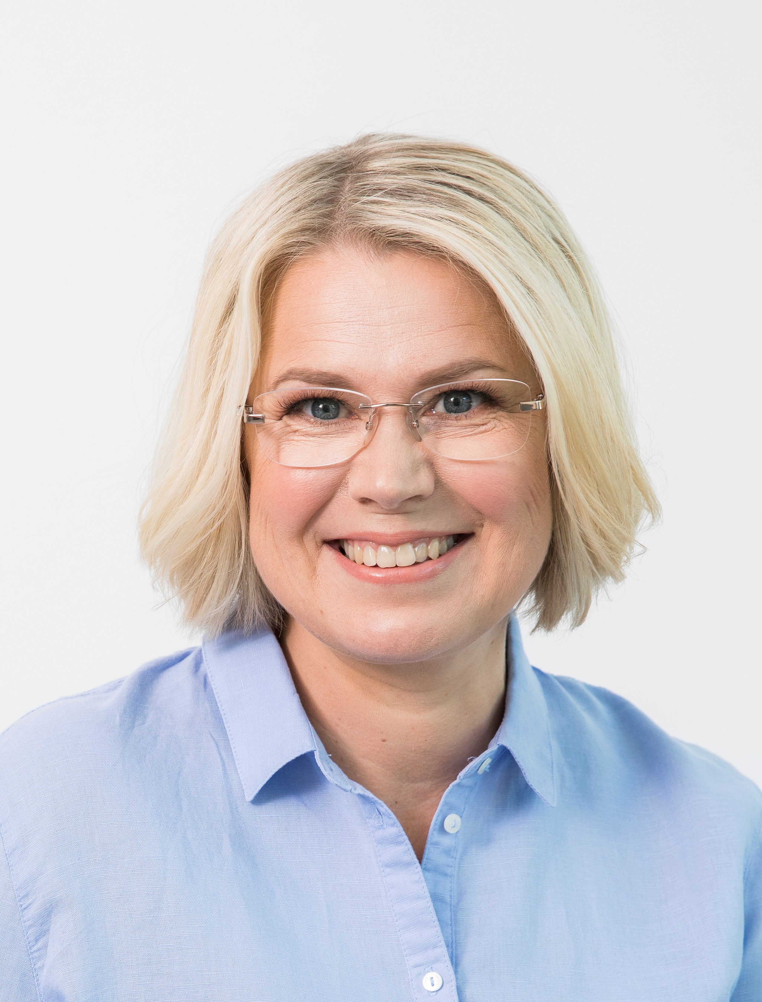 Vaaleatukkainen keski-ikäinen nainen päällään vaaleasininen kauluspaita.