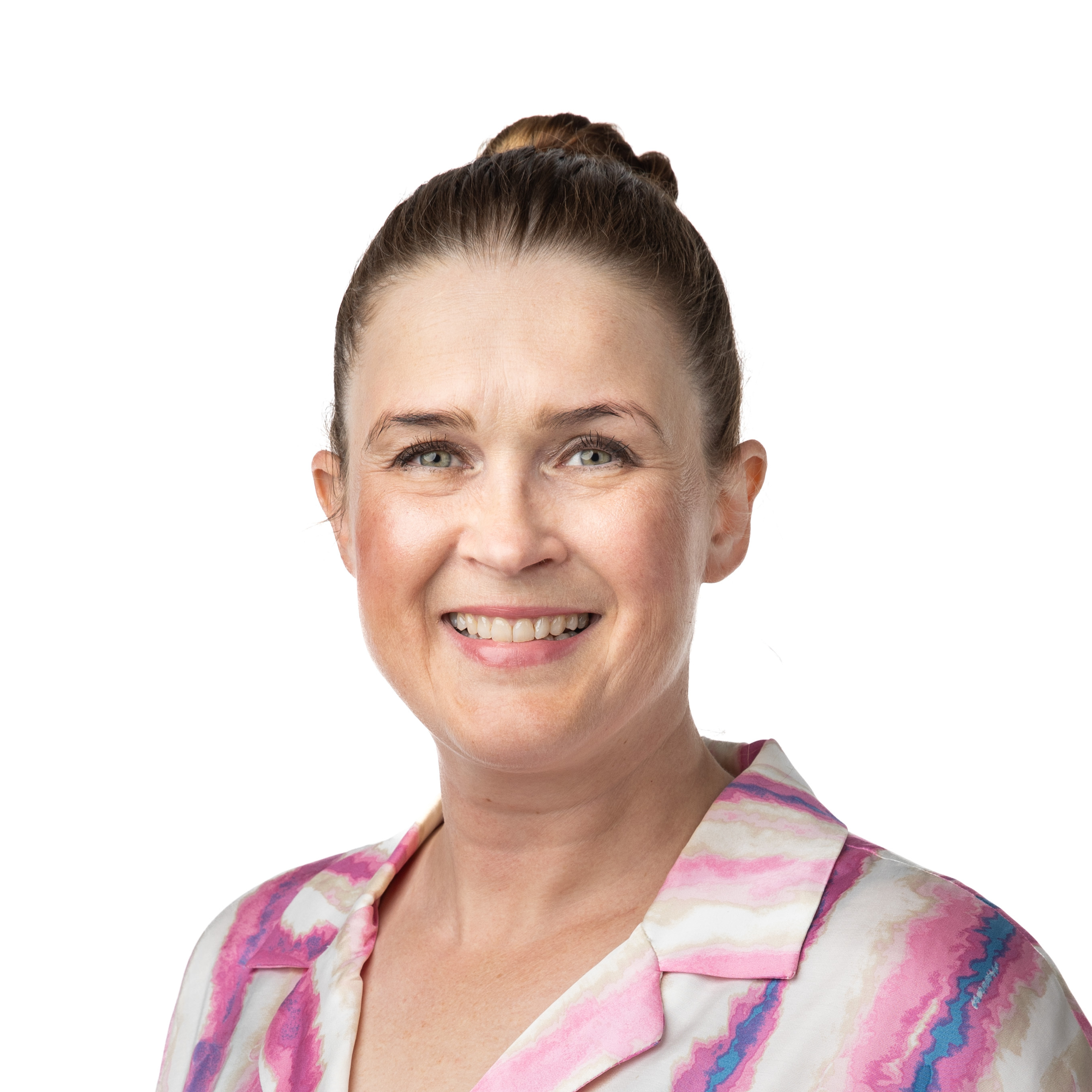 Toisessa kuvassa nainen, jolla on hiukset kiinni, hymyilee kameralle vaaleaa taustaa vasten ja käyttää kuviollista paitaa.